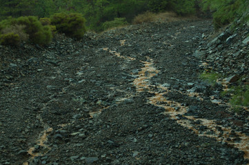 Mountain uneven dirt road with puddles. gray relief