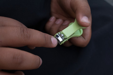 Closeup of man trims his fingernails using a metallic pair of nail clippers