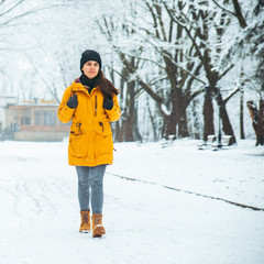 Fototapeta na wymiar woman walking by snowed city park. winter beauty