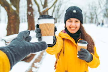 woman give cup of coffee to friend. meeting in snowed winter park