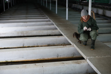 Woman checking fish reservoirs, writing in notebook