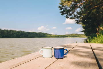 two metal cups with tea. river on background. summer time concept