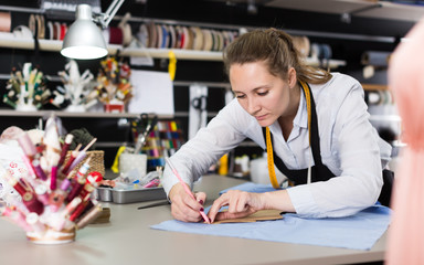 Woman  tailor working with marker for modeling clothes at workshop