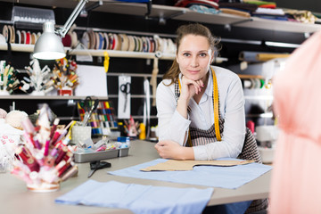 Portrait of female seamstress is who is posing in her design studio