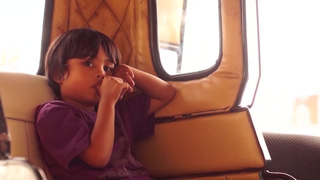 Little boy sucks thumb while alone in a tricycle