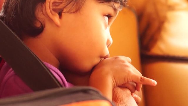 Little boy sucks thumb while alone in a tricycle