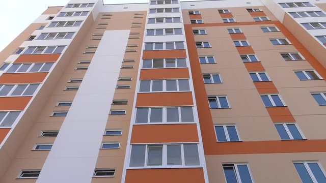 Facade of a multi-storey panel house the blue sky and clouds. New multystoried house.