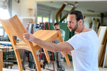 young worker in a carpenter's workshop with wooden chair