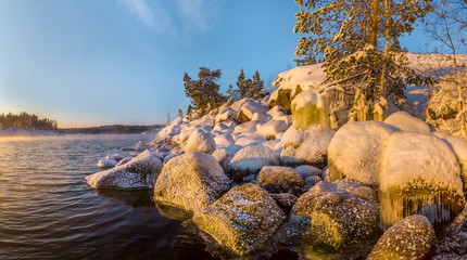 Ice stones, stones in the ice, ice. Sunset on the winter lake. Fog from heavy frost, soaring water at sunset. Winter Ladoga Lake.