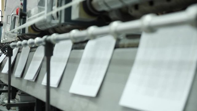 Book pages fall on the tape and move along a conveyor belt to a print shop.
