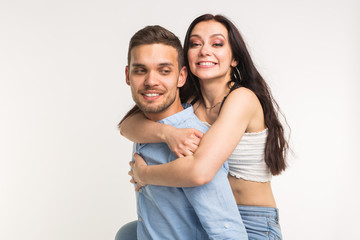 Fototapeta premium Emotional, love and people concept - young woman climbed the guy on the back and they happy and smile