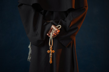 Monk holds wooden rosary and cross in hands