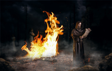 Medieval monk reads a prayer against a big fire