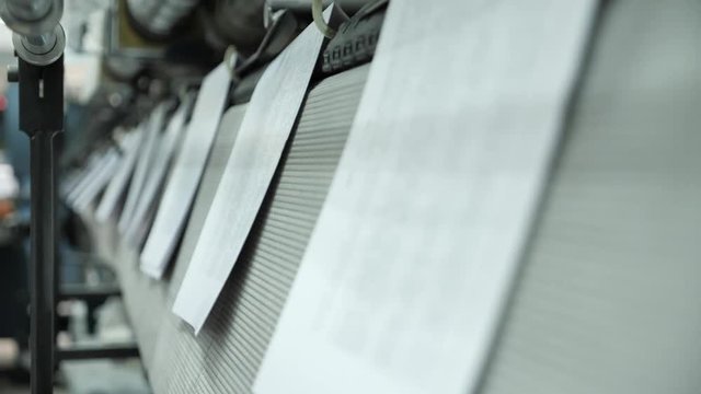 Book pages fall in slow motion on the tape and move along a conveyor belt in professional printing house.