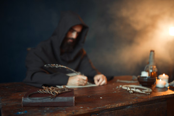 Medieval monk in robe writes with a goose feather - obrazy, fototapety, plakaty