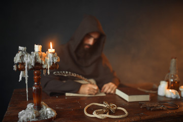 Fototapeta na wymiar Medieval monk sitting at table and write, top view
