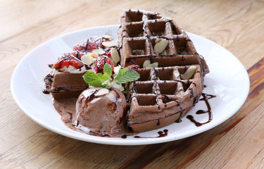 Close up of chocolate ice cream with waffle and fresh strawberry on wood table background