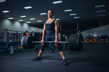 Fototapeta na wymiar Male powerlifter preparing deadlift barbell in gym