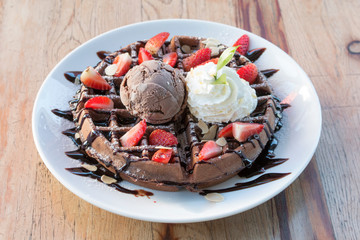 Close up of chocolate ice cream with waffle and fresh strawberry on wood table background