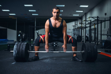 Fototapeta na wymiar Male powerlifter preparing deadlift barbell in gym