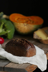 Bread at the table with vegetables on dark background