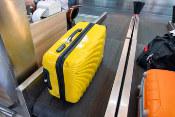 Yellow large luggage on belt at counter airline