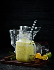 Fresh blended cocktail of green apples, kiwi and avocados in a glass cup. On a wooden background....