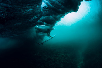 Surfer with surfboard dive underwater with under big wave.