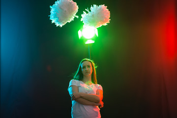 Cheerleading young woman dancing with pom-poms on colourful background © satura_