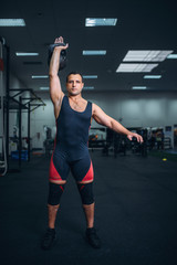 Obraz na płótnie Canvas Man in sportswear doing exercise with kettlebell