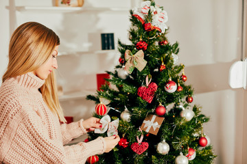 Portrait of beautiful woman with christmas presents near christmas tree.