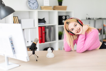 A young girl with headphones standing at a table in the office.