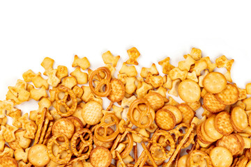 Many salty crackers, sticks, pretzels, and goldfishes, shot from above on a white background with copy space. Party snacks mix with a place for text - obrazy, fototapety, plakaty