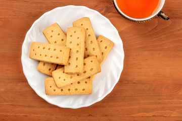 A photo of Scottish shortbreads, butter cookies, shot from the top on a rustic background with a vintage tea cup and copy space