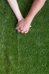 Lovers couple holding hands stay on green artificial grass valentines concept