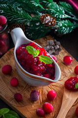 Cranberry sauce in a gravy boat on a wooden board, selective focus