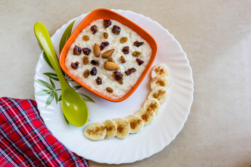 Oatmeal in bowl with banana and dry fruits