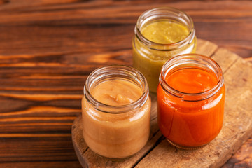 Variation pureed baby food in glass jars on cutting board