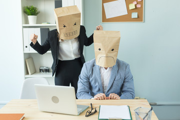 Fototapeta na wymiar Business, emotions and people concept - Two angry and exhausted workers at working place. People wearing the packages on their heads with pictured emotions