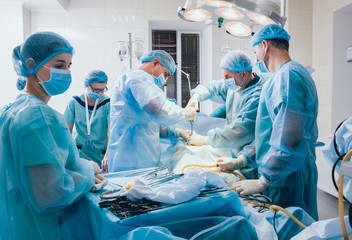 Process of gynecological surgery operation using laparoscopic equipment. Group of surgeons in operating room with surgery equipment