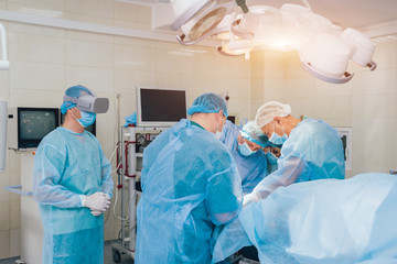 Doctor in a surgical room with virtual reality glasses on the background of the real operation.