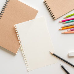blank paper with spiral notebook, pencil, eraser and color pencil on white background. Empty Space for your Text.