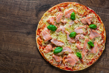 Pizza with Mozzarella cheese, salmon fish, tomato sauce. Italian pizza on wooden table background