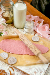 Fototapeta na wymiar Rolling pin with a pattern on a wooden decorated table covered with baked flour. Rolled dough with a pattern and cookie of various shapes. Biscuit cooking background, top view