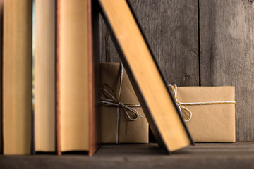 A gift hidden on a wooden shelf behind the books.