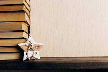Books and a Christmas tree with cones, and a star decoration on an old wooden shelf. Copy space, the concept of reading in the winter.