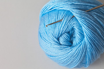 Skein of blue yarn for hand knitting and crochet hook. Empty place for text. Light gray background