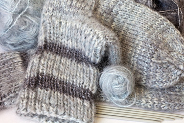 Fototapeta na wymiar Needlework. Hand-knit warm socks made from fluffy natural mohair gray yarn and the five needles for knitting
