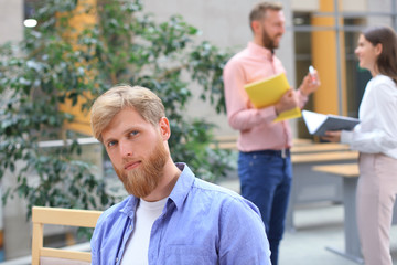 Portrait of young man sitting at his desk in the office, working on his PC.