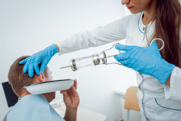Medical ear washing with water in big syringe